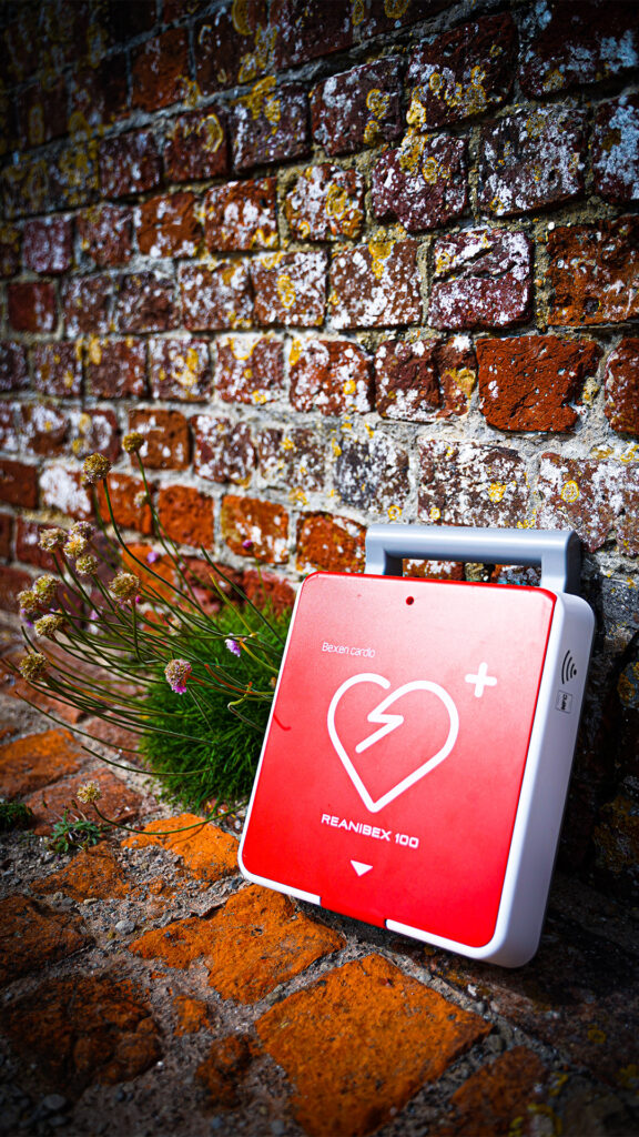 Image of a defibrillator placed by a brick house wall
